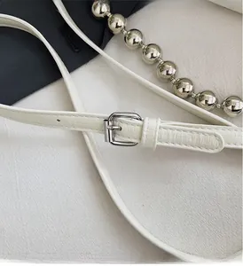 Detail of white leather strap with silver metal buckle and decorative silver bead chain