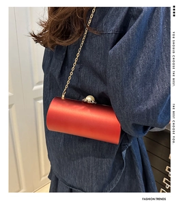 Détail du sac de soirée cylindrique en satin rouge avec fermoir perle et chaîne dorée