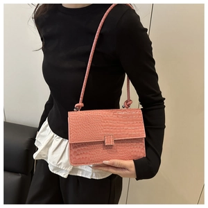 Close-up of pink crocodile pattern bag with sleek flap and matching shoulder strap