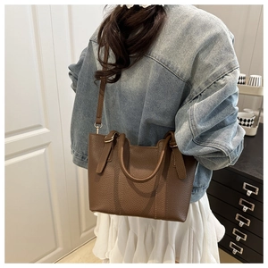 Brown lychee leather bucket bag shown on a model with a blue denim jacket