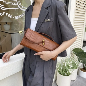 Pochette marron motif crocodile avec boucle dorée et bandoulière sur mannequin en gris