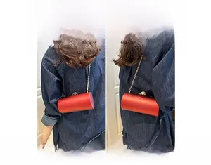 Sac de soirée cylindrique en satin rouge avec bandoulière dorée et fermoir perle