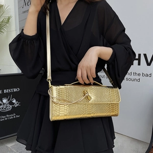 Sac à main doré motif serpent avec fermoir torsadé porté par un mannequin en robe noire