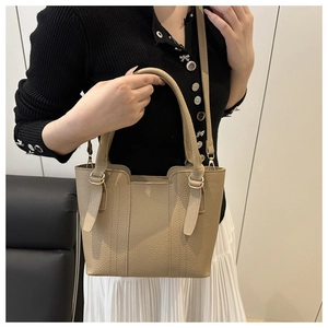 Detail of beige lychee pattern leather bucket bag with metal rings and adjustable strap