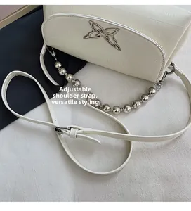 Detail of white crocodile texture bag with silver butterfly and adjustable strap