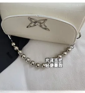 Close-up of cream beaded shoulder bag with faux crocodile pattern and butterfly logo