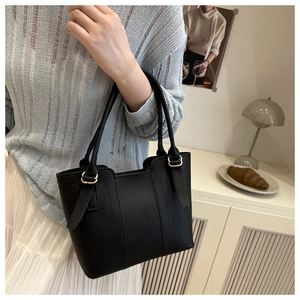 Detailed shot of black lychee grain leather tote bag featuring gold metal hardware