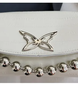 Detail of white leather handbag with silver butterfly buckle and chunky metal bead chain