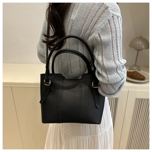 Detailed close-up of black lychee texture leather handbag with elegant gold metal hardware