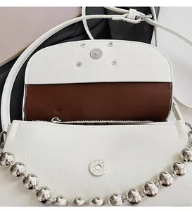 Detail of white crocodile texture shoulder bag with magnetic clasp and silver beaded chain