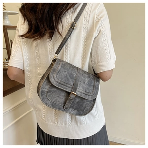 Detailed back view of model wearing a vintage grey saddle bag with golden hardware
