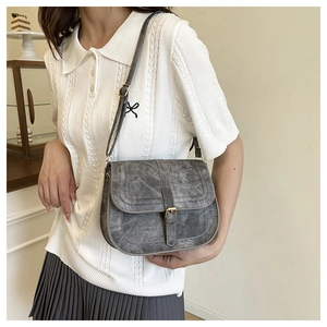 Retro grey saddle bag detail showing matte texture and adjustable strap on a model