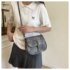 Close-up of a vintage grey washed saddle bag with retro bronze buckle detail