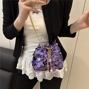 Purple sequin bucket bag with gold chain and pearl drawstring on a mirror selfie