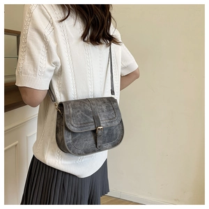 Detailed view of gray vintage saddle bag with textured leather and metal buckle on model
