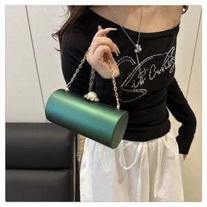 Détail du sac de soirée cylindrique vert foncé avec fermoir perle et bandoulière dorée