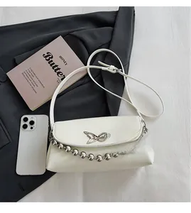 Close-up of beaded white shoulder bag with butterfly metal logo and silver chain strap