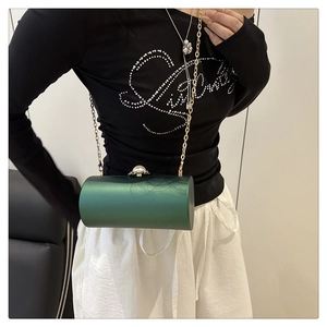 Détail du sac cylindrique en acrylique vert foncé avec fermoir perle et fine chaîne dorée