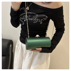 Gros plan sur un sac de soirée cylindrique en acrylique vert avec chaîne dorée et perle