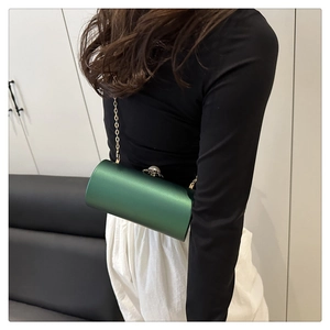 Détail du sac de soirée cylindrique vert avec chaîne dorée et fermoir perle