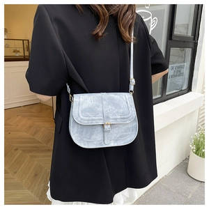 Light blue vintage saddle bag with gold buckle on a model in a street style setting