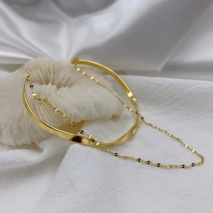 Minimalist double-layer gold twist chain open bangle on a textured white coral stone base