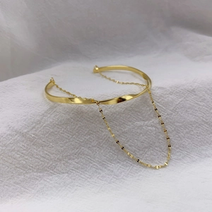 Minimalist gold twisted open bangle featuring a delicate double layer chain accent