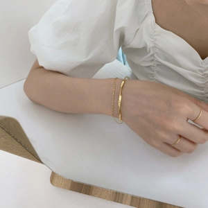 Detail shot of a layered gold twisted chain bracelet and matching rings on a model