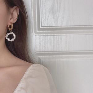 Detail of vintage gold hoop earring featuring a ring of lustrous white pearls on a model