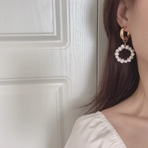 Close-up of a model wearing vintage gold hoop earrings with elegant white pearls