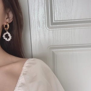 Elegant gold hoop earrings with white faux pearls shown on a female model profile