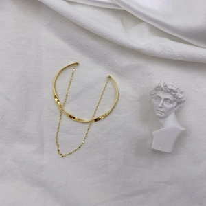 Minimalist gold-plated twisted chain cuff bracelet shown on aesthetic marble backdrop