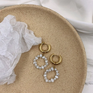Vintage irregular gold circle earrings with artificial pearl loops on a textured tray