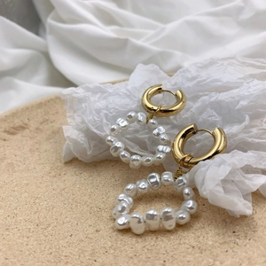 Detail shot of vintage golden hoop earrings with irregular baroque pearl circle charms