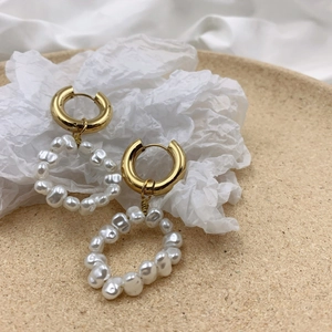 Elegant gold hoop earrings with white pearl circle pendants on a minimalist background
