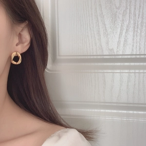Close-up of gold irregular twisted hoop earrings on model for size and minimalist design