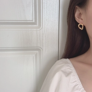 Close-up of a minimalist irregular geometric gold earring worn by a model