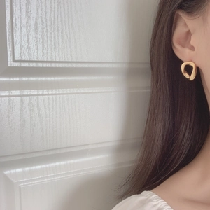 Close-up of elegant gold twisted irregular geometric earrings worn by a model