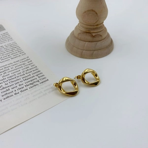 Irregular geometric gold earrings with wavy design on a minimalist white setting