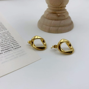 Irregular geometric gold earrings with minimalist twisted design on a neutral background