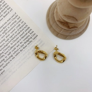 Detailed macro view of golden irregular twisted hoop earrings on vintage book page