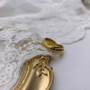 Detail eines goldenen geflochtenen Kettenrings auf antikem Rahmen und weißer Spitze