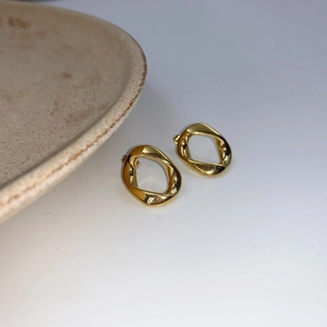 Macro shot of gold geometric irregular twisted hoop earrings with polished mirror finish