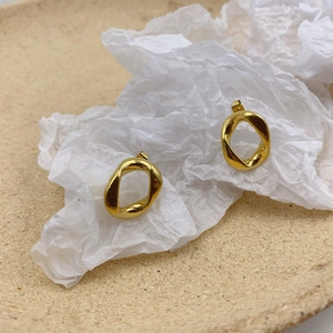 Detailed close-up of golden irregular twisted hoop earrings with liquid metal texture