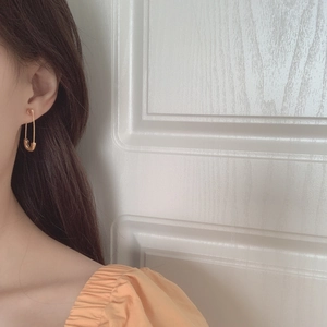 Vue détaillée d'une boucle d'oreille épingle à nourrice dorée portée avec style épuré