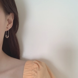 Gros plan sur les boucles d'oreilles épingle de sûreté en argent au style minimaliste