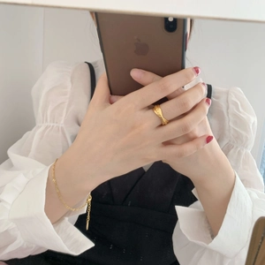Detailansicht eines breiten goldenen Flechtrings und feinen Kettenarmbands