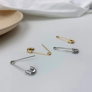 Boucles d'oreilles épingle à nourrice minimalistes dorées et argentées sur fond blanc