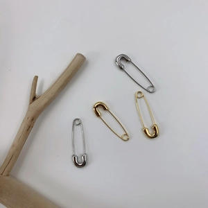 Vue à plat de boucles d'oreilles épingle de sûreté dorées et argentées avec branche bois