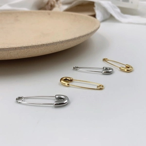 Vue macro de boucles d'oreilles épingles de sûreté minimalistes en or et argent